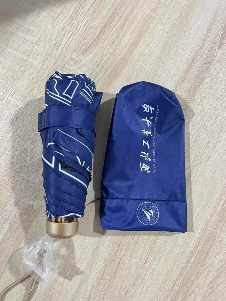 Blue NPU folding umbrella beside a sleeve bearing the university name and emblem