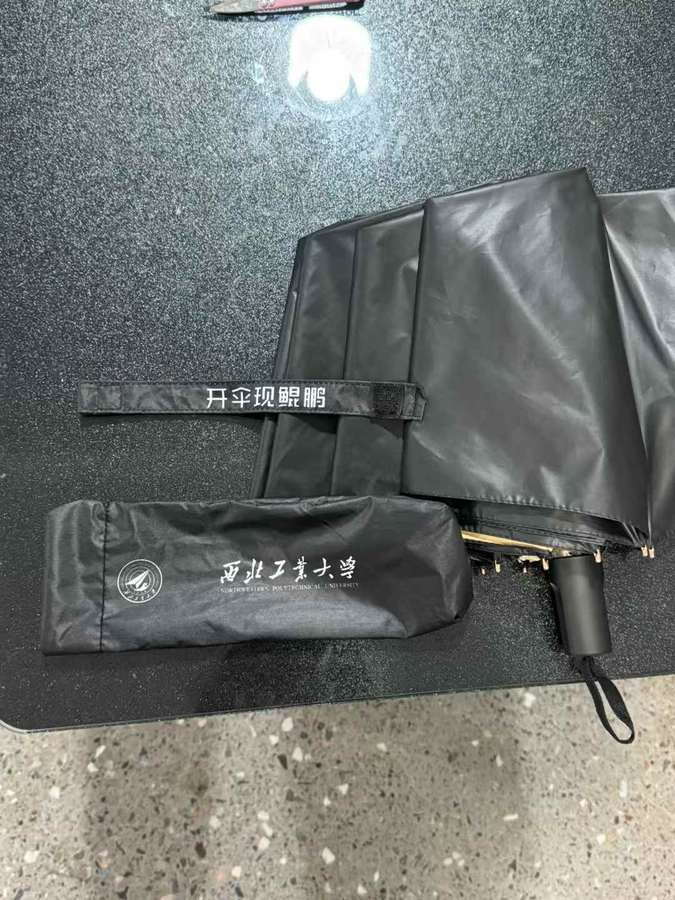 Black NPU umbrella with a branded sleeve and lettering on the fastening strap